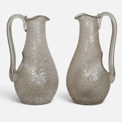 une paire de vases en verre argenté posés sur une surface blanche, sur fond blanc