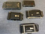five old cell phones sitting on a blue surface