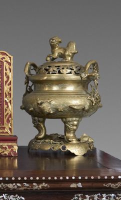 une horloge dorée et rouge posée sur une table en bois