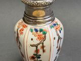 a small white vase with a silver lid on a table