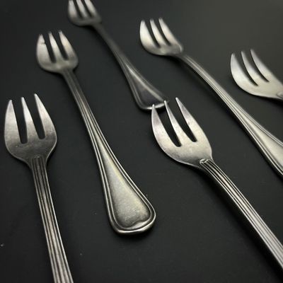 cinq fourchettes et deux cuillères sur une table noire
