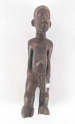 an old wooden statue of a man standing with his hands in his pockets