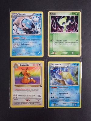quatre cartes Pokémon différentes posées sur une table noire