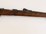 un vieux fusil en bois accroché au mur, à côté d'un mur blanc