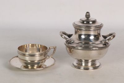 une théière en argent et une tasse en argent posées sur une table