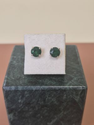 a pair of green stone stud earrings sitting on top of a marble block