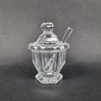 un bocal en verre transparent avec une cuillère et un repose-cuillère posés sur une surface noire