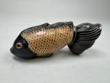 une petite figurine représentant un poisson sur un fond blanc