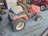 un tracteur orange garé dans un garage avec d'autres tracteurs