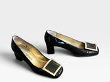 deux paires de chaussures noires et dorées posées sur une surface blanche