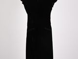 a black dress on a mannequin stand with a white background
