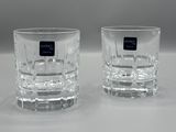 une paire de verres à eau en verre transparent, ornés d'étiquettes noires, posés sur une surface blanche