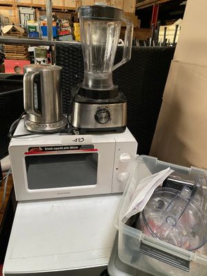 a blender sitting on top of a microwave next to a container