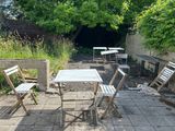 tables and chairs set up in a courtyard area with trees in the background