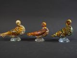 three glass birds sitting on top of each other on a black surface