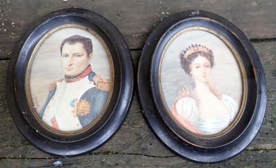 deux portraits encadrés représentant un homme et une femme, posés sur une surface en bois