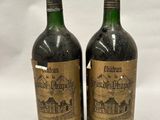 two bottles of wine sitting next to each other on a white surface