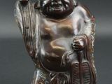 une image représentant une statue d'un Bouddha souriant tenant un bâton
