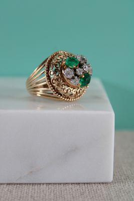 gros plan d'une bague en or avec des pierres vertes et blanches