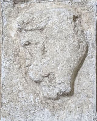 relief of a man ' s face on a stone block