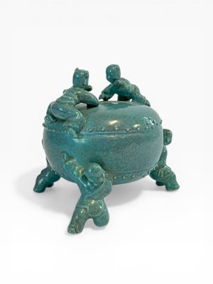 un petit pot vert orné de trois oiseaux