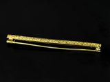 a close up of a gold hair clip on a black surface
