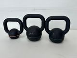 three black kettle weights sitting on top of a white table