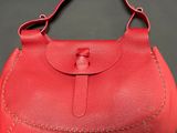 a red leather purse with a metal clasp on the handle
