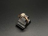 une image représentant une bague en or sertie d'un diamant, posée sur un socle noir
