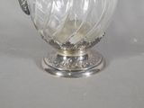 a glass vase with a silver handle on a table