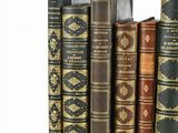 several old books are stacked on top of each other on a white surface