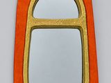 an orange and gold mirror sitting on top of a white wall