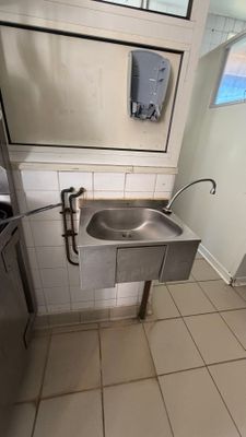 a stainless steel sink in the corner of a bathroom