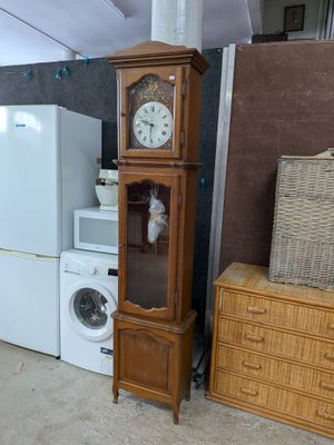 une grande armoire en bois surmontée d'une horloge, à côté d'un lave-linge et d'un sèche-linge