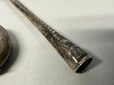 a silver pocket watch and a silver baseball bat on a table