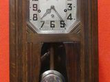 une horloge en bois accrochée au mur, avec un mur rouge en arrière-plan