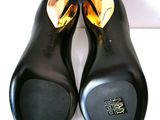 pair of black leather shoes with gold accents on a white surface