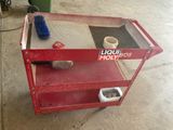 a red cart with a bottle of liquid and a brush on it