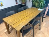 une table en bois avec des chaises et une plante dans un coin