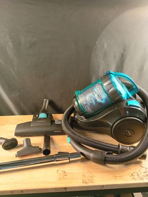 un gros plan d'un aspirateur posé sur une table en bois, à côté d'autres outils