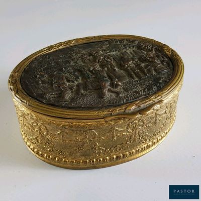 une boîte dorée ornée d'une image, posée sur une surface blanche