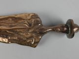 a bronze object on a white surface with a gray background