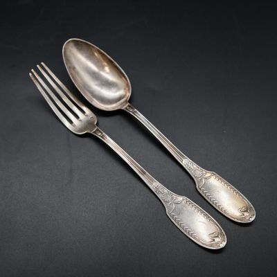 two silver spoons and a fork on a black background