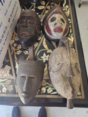 three masks on the floor next to a sign