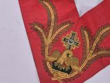 two pieces of red cloth with gold embroidery on them sitting on a table
