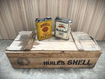 two cans of shell oil sitting on top of a wooden box
