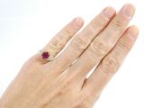 a woman ' s hand with a diamond and ruby ring on it