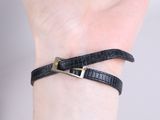 a close up of a person ' s hand wearing a black leather bracelet with a gold buckle