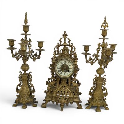 three candlesticks and a clock on a white background
