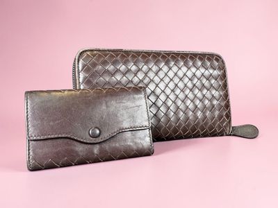 a pair of brown leather wallets on a pink background